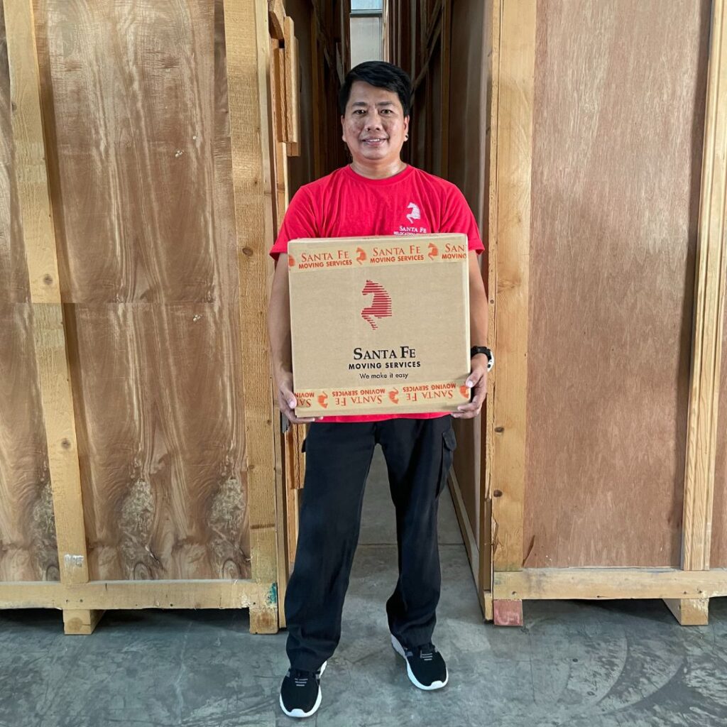 Member of the Santa Fe packing team holding a Santa Fe box, ready to help our next customer moving internationally.