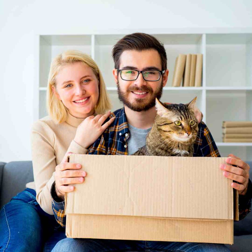 couple smiling with a cat in a cupboard box