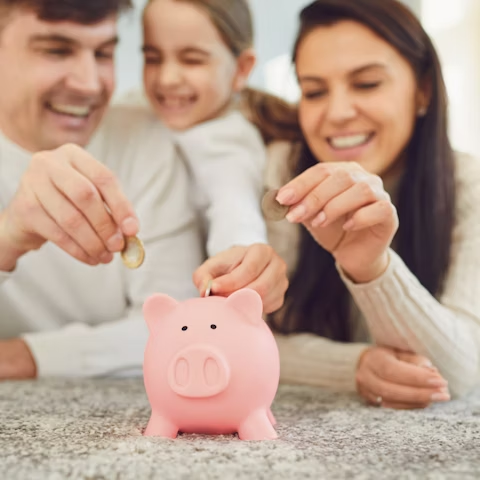 family putting their money into a piggie bank