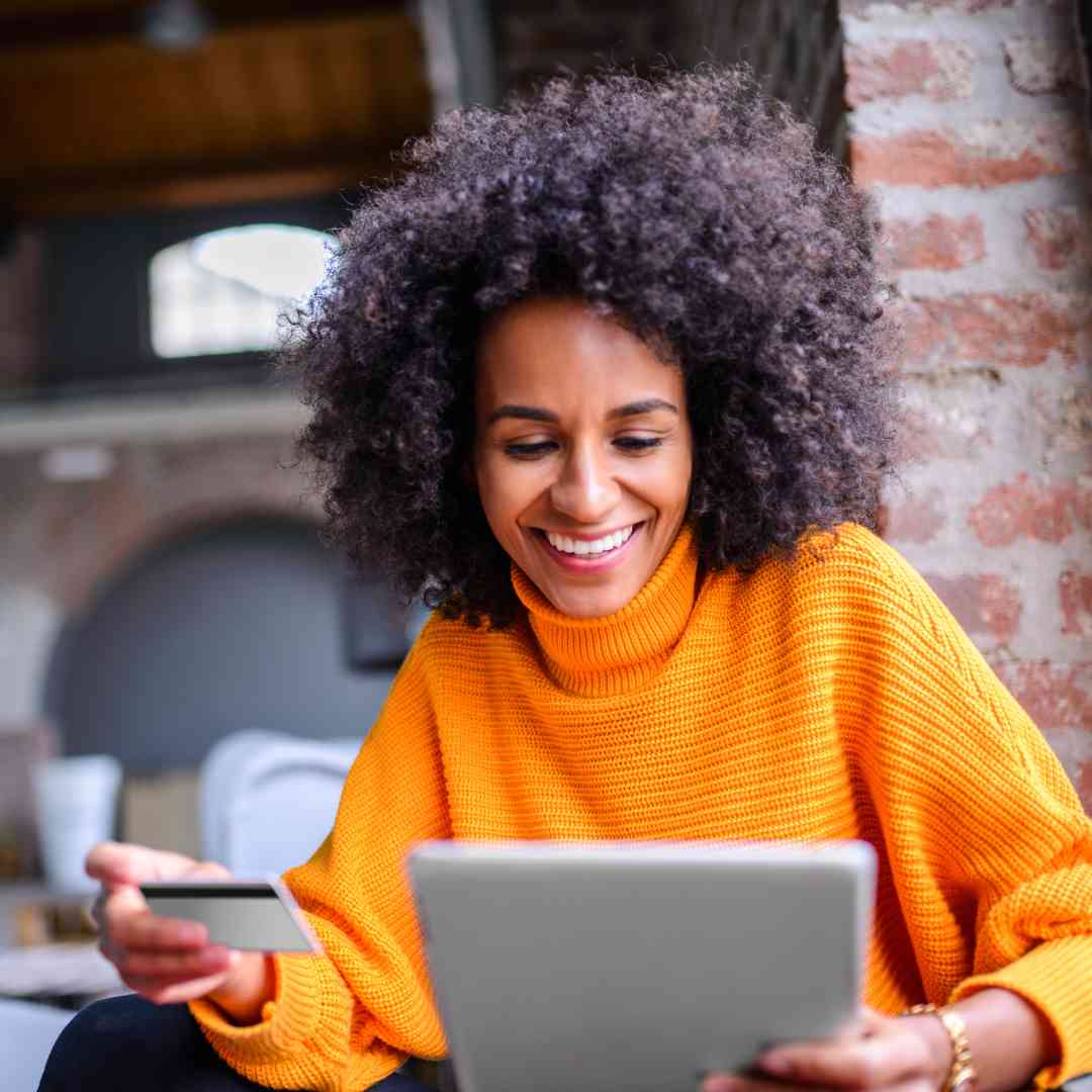 woman smiling at her laptop paying for something