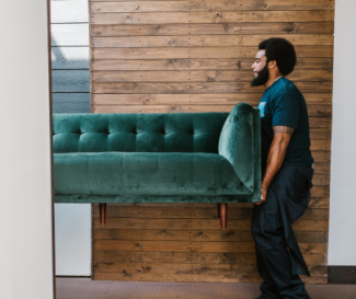 Santa Fe Relocation mover carefully carrying a green velvet sofa, showcasing the company’s commitment to seamless and stress-free international moving services.