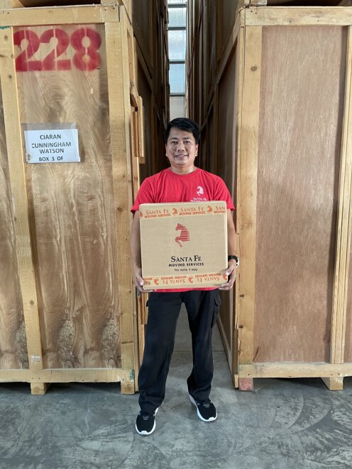 Member of the Santa Fe packing team holding a Santa Fe box, ready to help our next customer moving internationally.