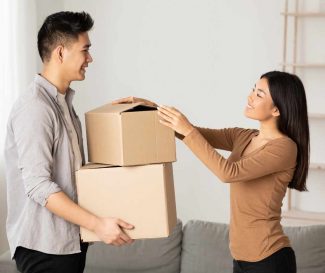 Woman and man in a room and the man is holding two cardboard boxes